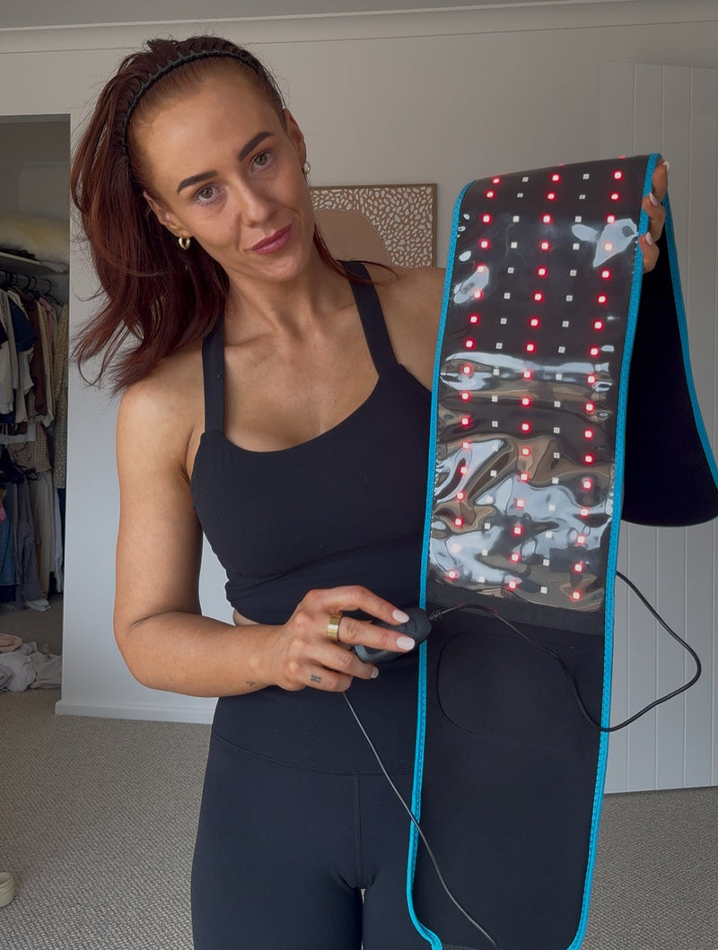 Woman holding a LED belt with a display in a room.